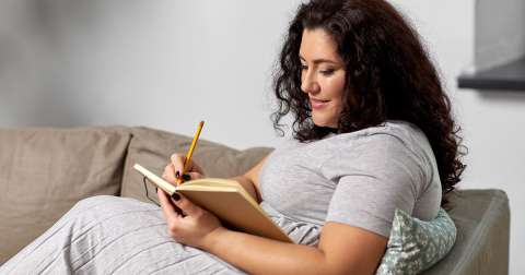 woman on couch with journal preparing for pregnancy