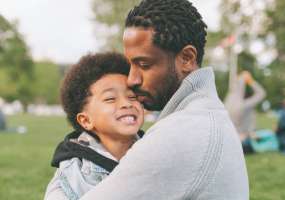 A man hugging his son at the park.